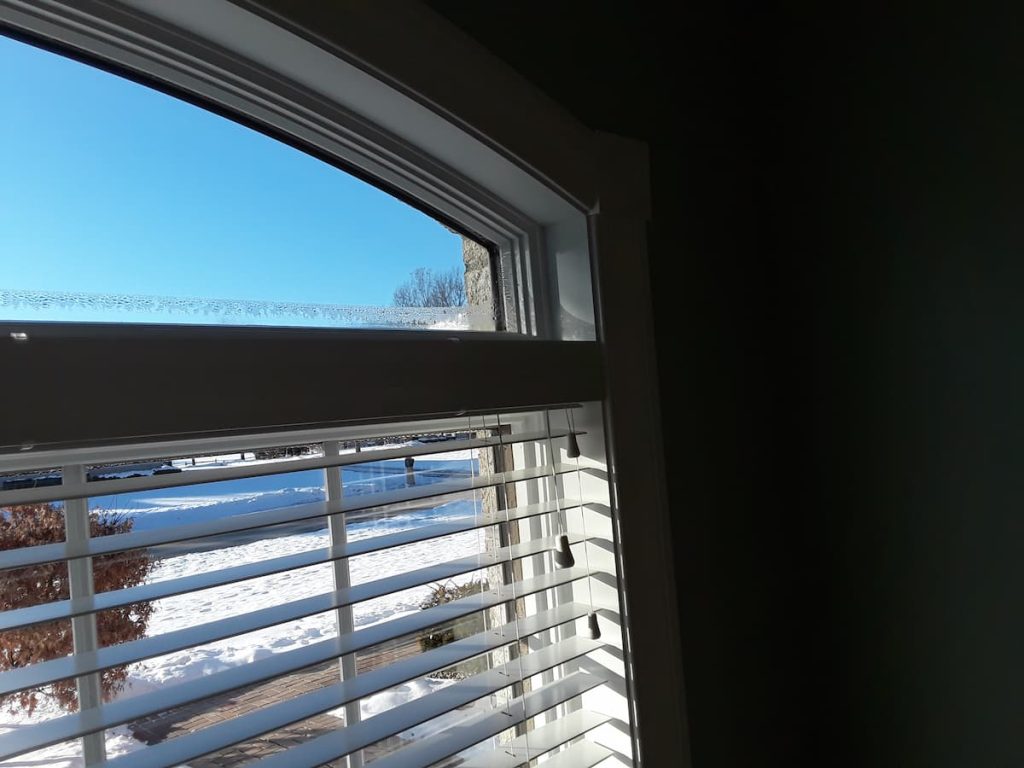 Window condensation forming along the bottom of a wood frame window during a Wisconsin winter